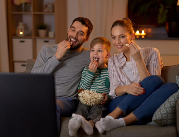 Man Woman And Child Eating Popcorn And Watching Tv On Couch