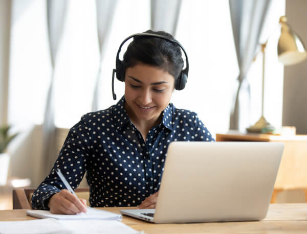 Woman Sitting At Desk Wearing Headset While Working On Computer