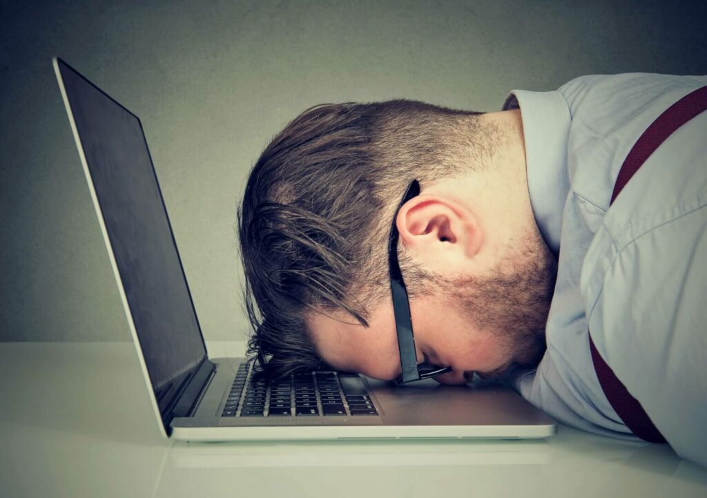 Overworked Man Lying On Laptop